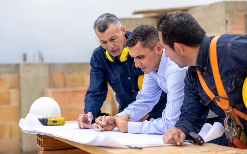 Construction workers examining architectural drawings